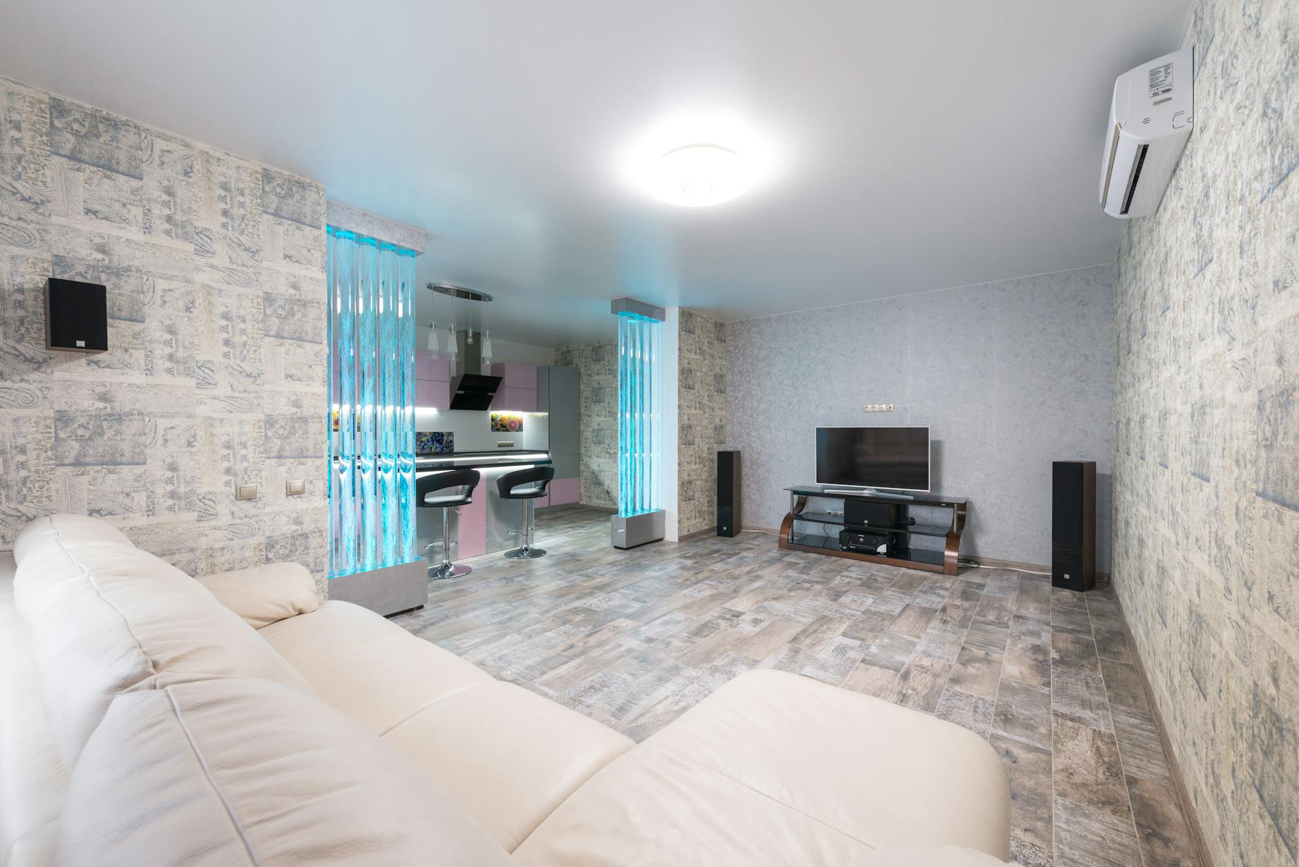 Jasny salon z białą sofą obok kuchni w nowoczesnym mieszkaniu