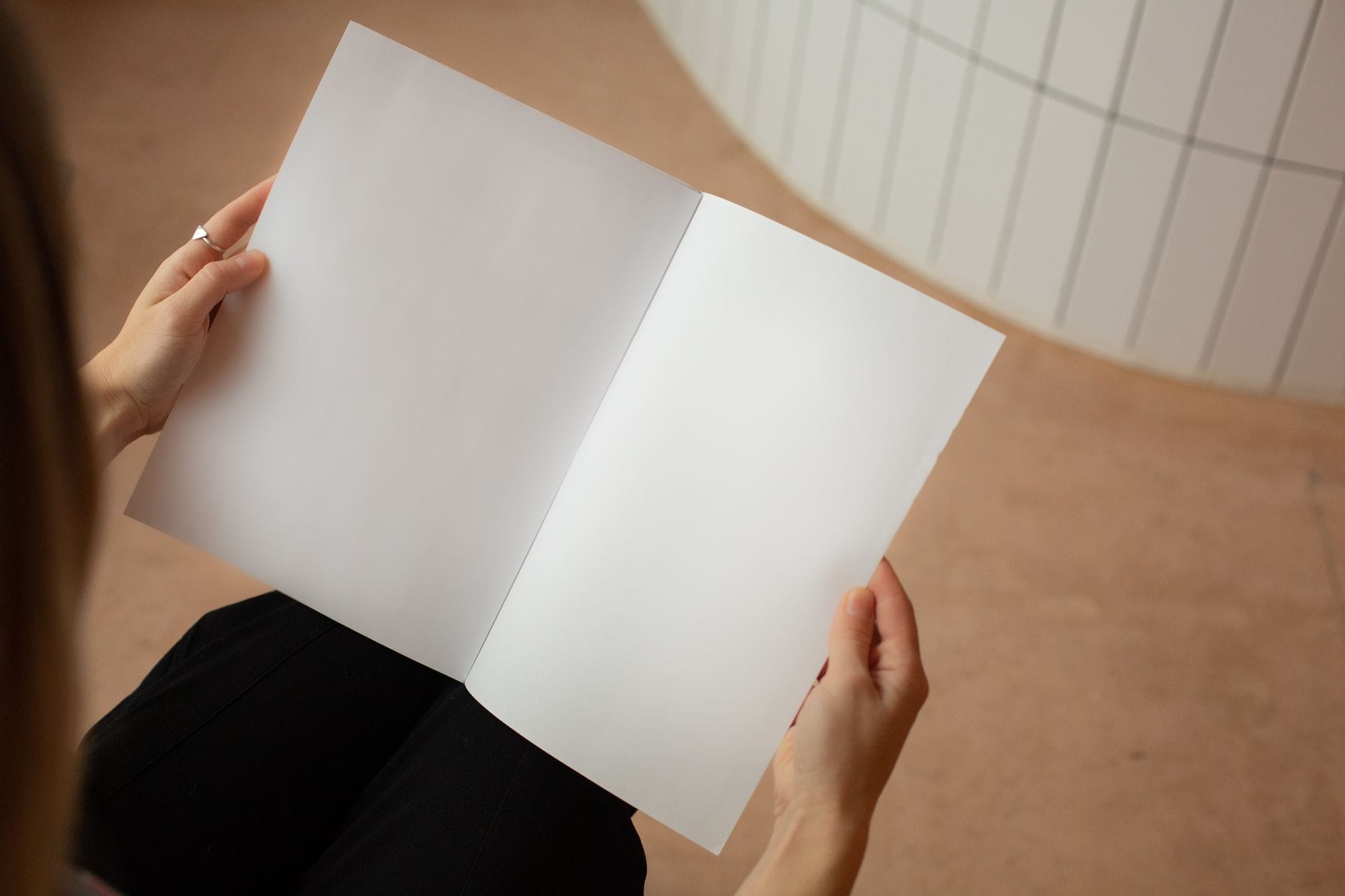 Kobieta siedzi w jasnym pokoju i ogląda białe kartki papieru