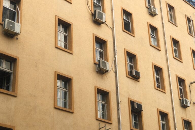 Ściana miejskiego budynku z klimatyzatorami i oknami w słoneczny dzień